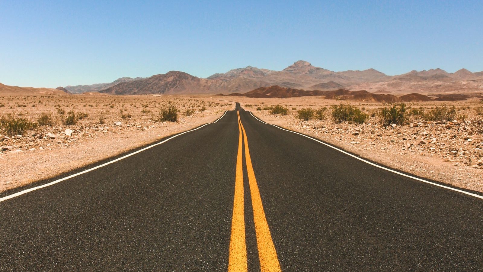 Long straight highway through the desert toward distant mountains
